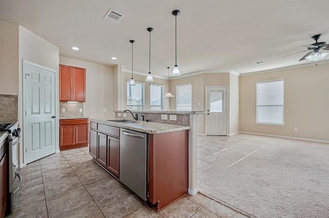 kitchen with sink, hanging light fixtures, appliances with stainless steel finishes, an island with sink, and light colored carpet