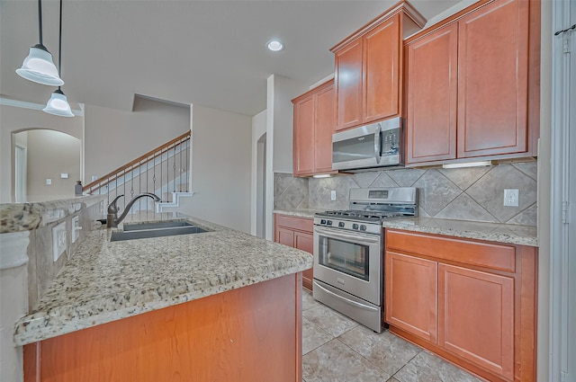 kitchen with light tile patterned flooring, sink, decorative light fixtures, appliances with stainless steel finishes, and decorative backsplash