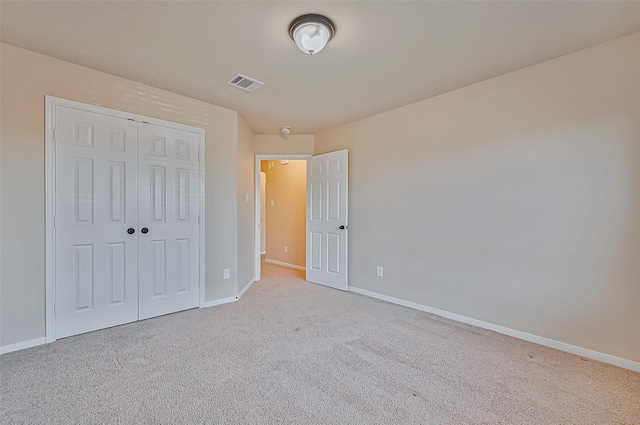 unfurnished bedroom featuring light colored carpet and a closet