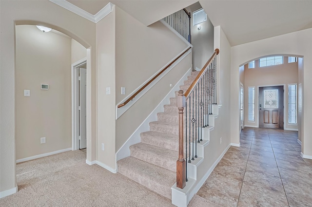 foyer with light carpet and crown molding