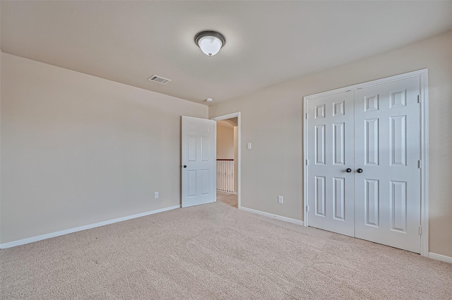 unfurnished bedroom with light carpet and a closet