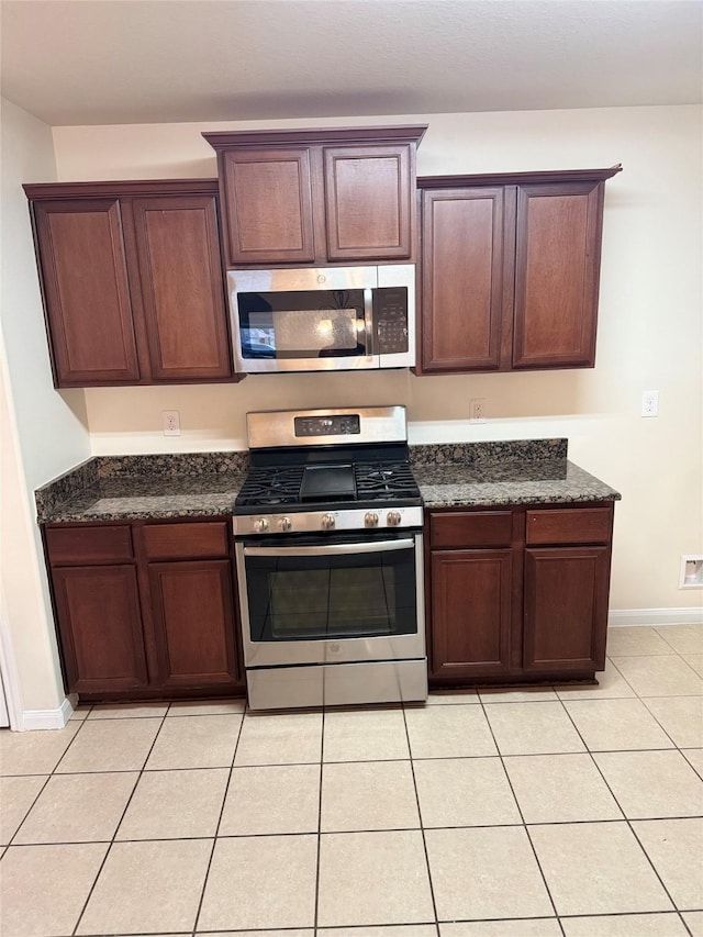 kitchen featuring dark stone countertops, appliances with stainless steel finishes, and light tile patterned floors