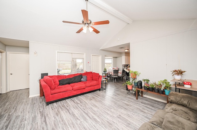 living room with ceiling fan, high vaulted ceiling, beam ceiling, and light hardwood / wood-style floors