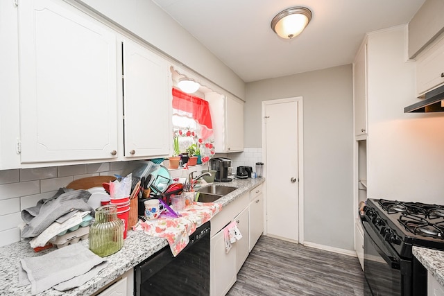 kitchen with dark wood-type flooring, light stone counters, black appliances, white cabinets, and backsplash