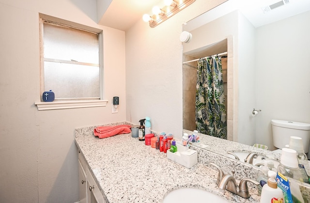 bathroom with vanity, curtained shower, and toilet