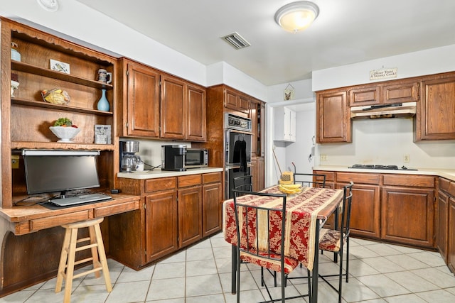 kitchen featuring multiple ovens, light tile patterned floors, and gas cooktop