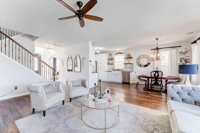 living room with dark hardwood / wood-style floors, ceiling fan with notable chandelier, and a textured ceiling