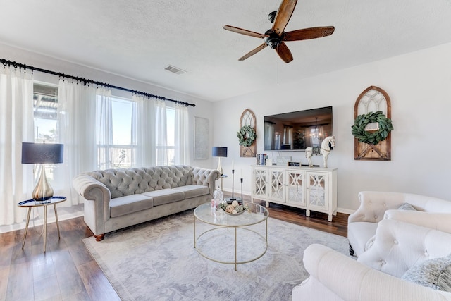 living room featuring ceiling fan, wood-type flooring, a textured ceiling, and a wealth of natural light