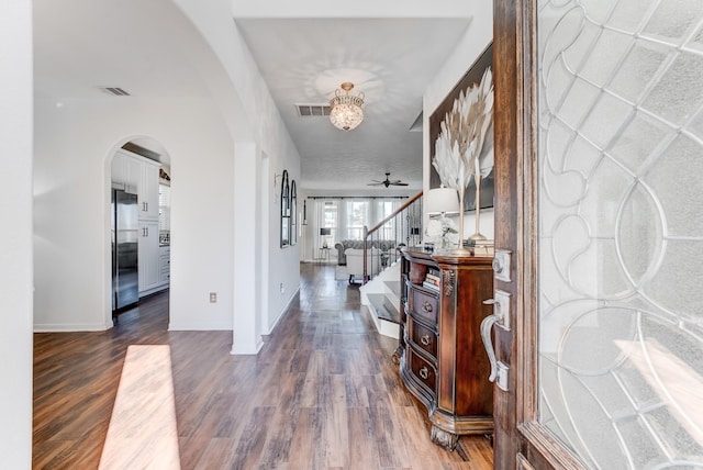 hall with dark wood-type flooring and an inviting chandelier