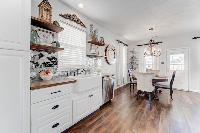 kitchen with dark wood-type flooring, sink, stainless steel dishwasher, pendant lighting, and white cabinets