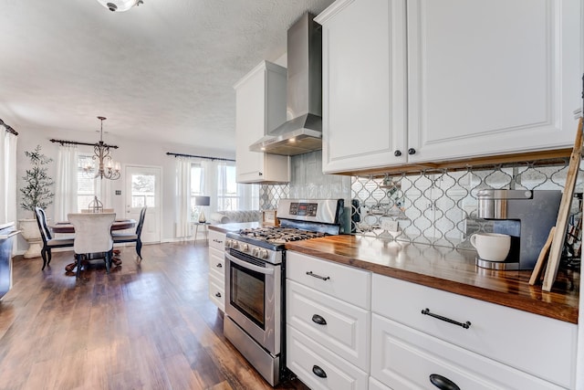 kitchen featuring wooden counters, white cabinetry, decorative light fixtures, stainless steel range with gas cooktop, and wall chimney exhaust hood