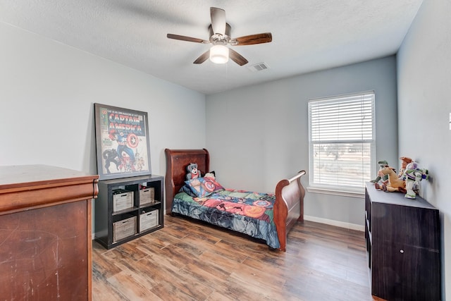 bedroom featuring ceiling fan, wood-type flooring, and a textured ceiling