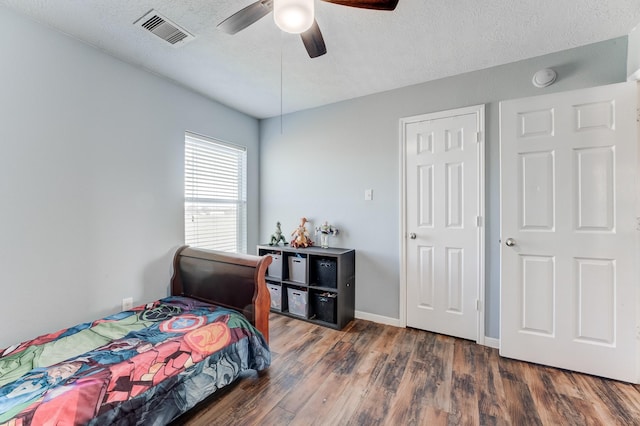 bedroom with a textured ceiling, dark wood-type flooring, and ceiling fan