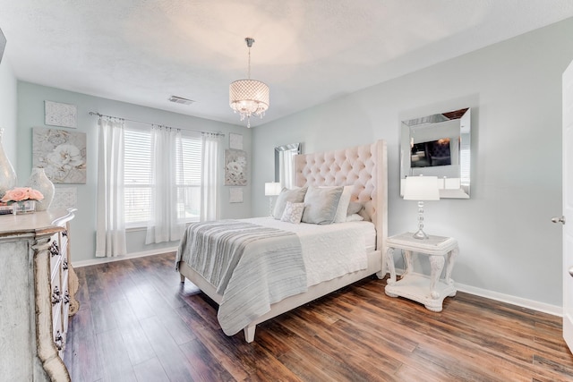 bedroom featuring dark hardwood / wood-style floors and an inviting chandelier