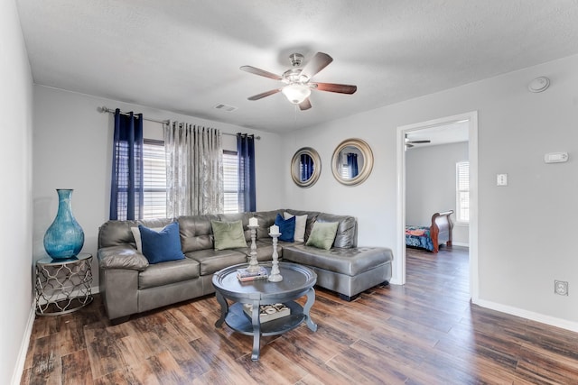 living room featuring dark wood-type flooring, a textured ceiling, and ceiling fan