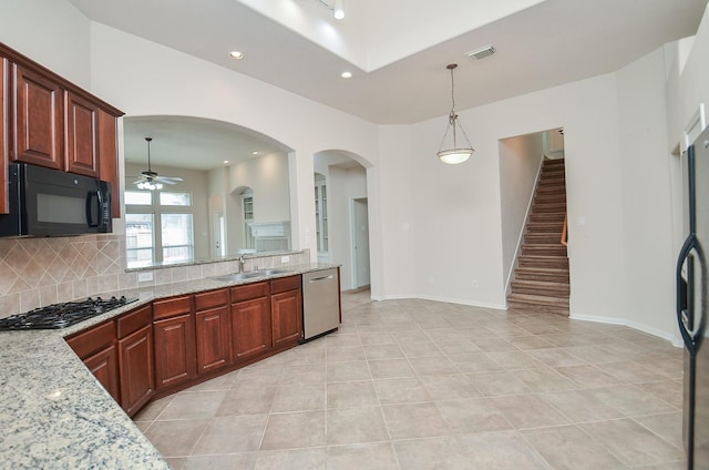 kitchen featuring appliances with stainless steel finishes, sink, decorative backsplash, hanging light fixtures, and light stone counters