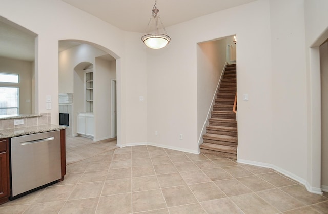 kitchen with pendant lighting, dishwasher, light stone counters, and light tile patterned floors