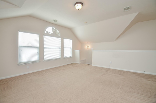 bonus room with vaulted ceiling and light carpet