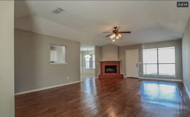 unfurnished living room with dark wood-type flooring, ceiling fan with notable chandelier, and a fireplace