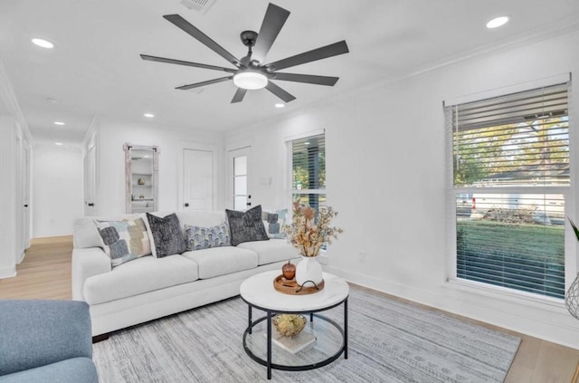 living room with ornamental molding, ceiling fan, and light hardwood / wood-style floors