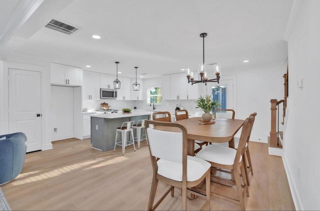 dining room featuring an inviting chandelier, ornamental molding, and light hardwood / wood-style flooring