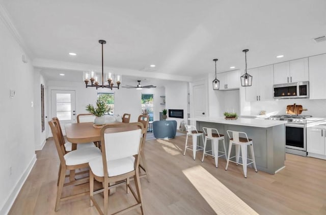 dining space featuring ornamental molding, ceiling fan with notable chandelier, and light hardwood / wood-style flooring