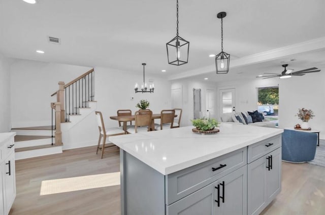 kitchen featuring hanging light fixtures, gray cabinets, a kitchen island, ceiling fan, and light hardwood / wood-style floors