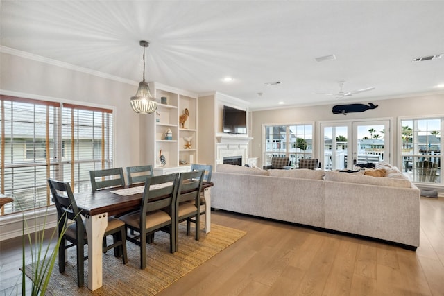 dining room with french doors, ornamental molding, a healthy amount of sunlight, and light hardwood / wood-style flooring