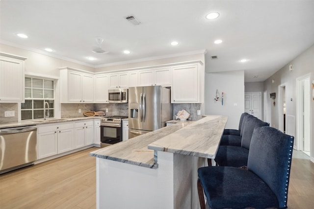 kitchen featuring sink, stainless steel appliances, light stone counters, tasteful backsplash, and white cabinets