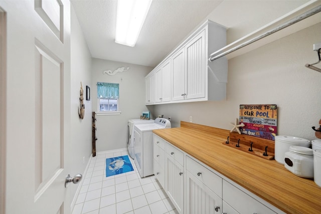 laundry area featuring cabinets, light tile patterned floors, a textured ceiling, and independent washer and dryer