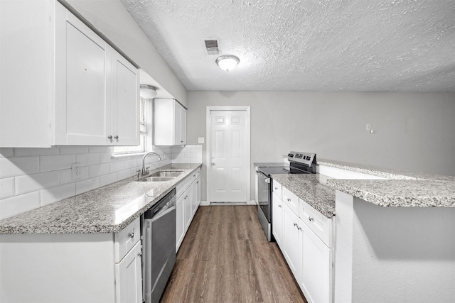 kitchen with sink, appliances with stainless steel finishes, white cabinetry, backsplash, and a textured ceiling