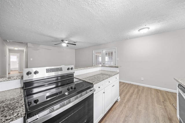 kitchen with appliances with stainless steel finishes, white cabinets, light stone counters, light hardwood / wood-style floors, and a textured ceiling