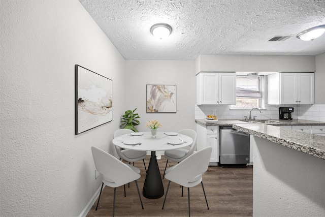 dining space featuring dark wood-type flooring, sink, and a textured ceiling