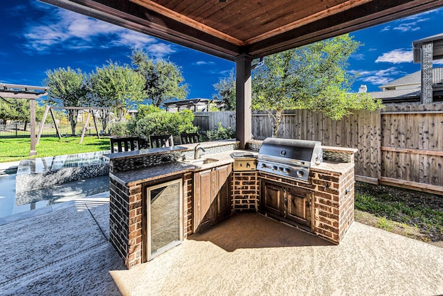 view of patio / terrace featuring a playground, an outdoor kitchen, a grill, and sink