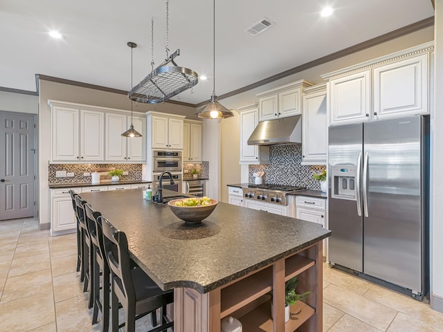 kitchen featuring pendant lighting, ornamental molding, appliances with stainless steel finishes, and an island with sink