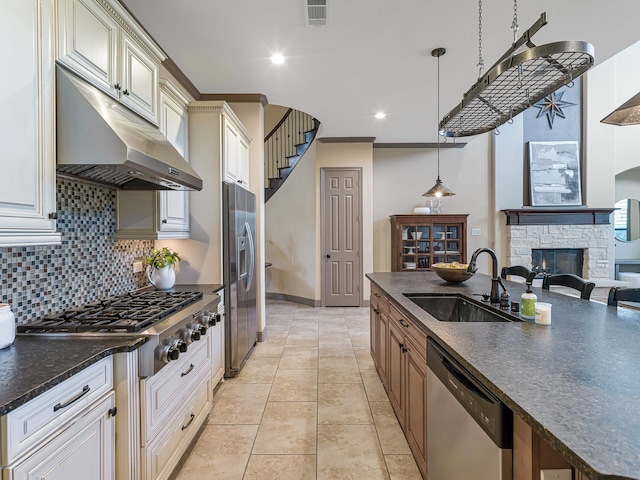 kitchen featuring pendant lighting, sink, stainless steel appliances, light tile patterned flooring, and a stone fireplace