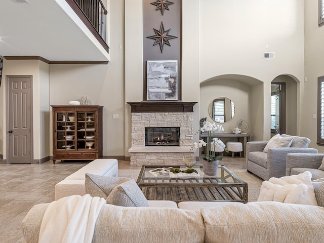 living room featuring a towering ceiling, light tile patterned floors, and a fireplace