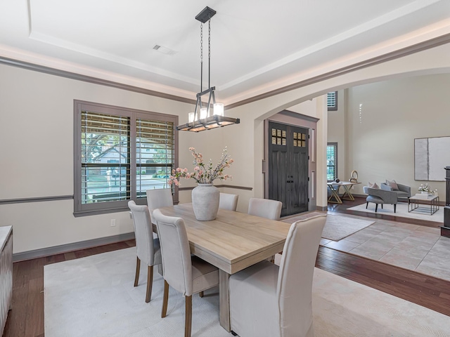 dining area featuring a tray ceiling, a chandelier, and light wood-type flooring