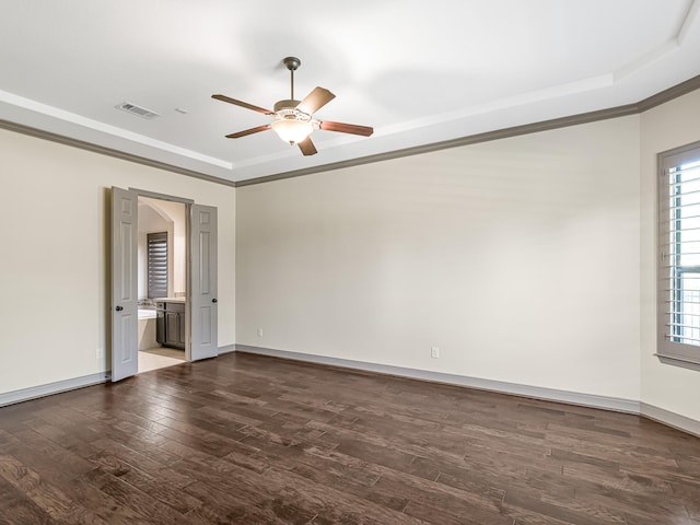 empty room with dark hardwood / wood-style flooring, crown molding, a tray ceiling, and ceiling fan