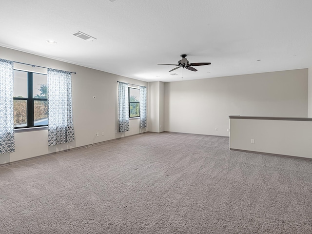 carpeted spare room with ceiling fan and plenty of natural light