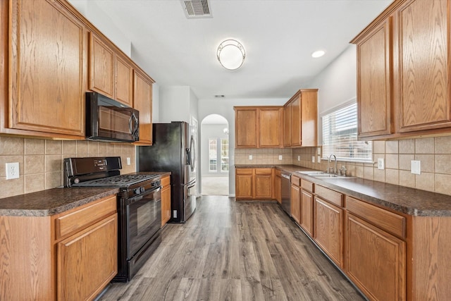 kitchen with hardwood / wood-style flooring, backsplash, sink, and black appliances