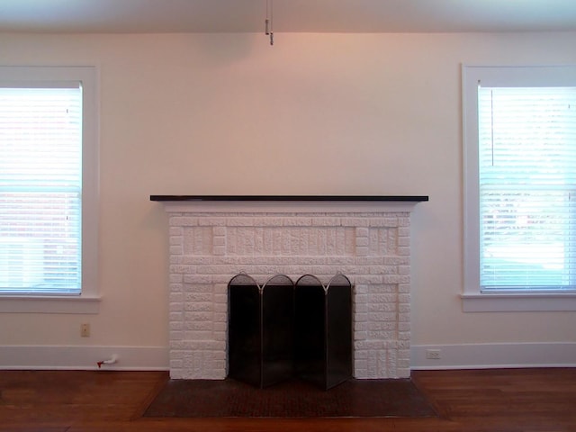 interior details with wood-type flooring and a brick fireplace