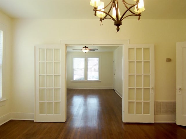 spare room with a notable chandelier and dark wood-type flooring