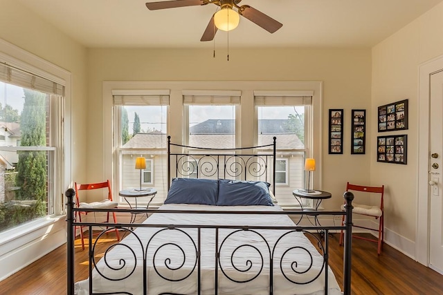 bedroom featuring multiple windows, dark wood-type flooring, and ceiling fan