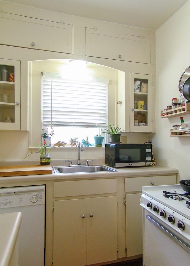 kitchen with sink, white cabinets, and white appliances