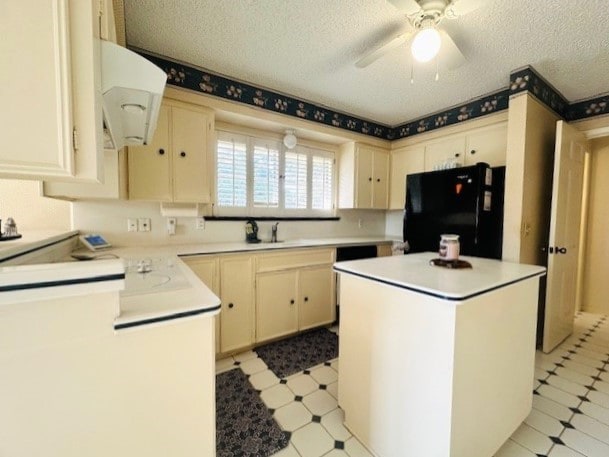 kitchen featuring light floors, light countertops, freestanding refrigerator, a textured ceiling, and extractor fan