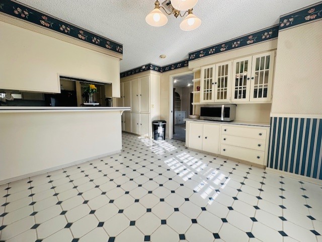 kitchen with hanging light fixtures, cream cabinets, a notable chandelier, and a textured ceiling