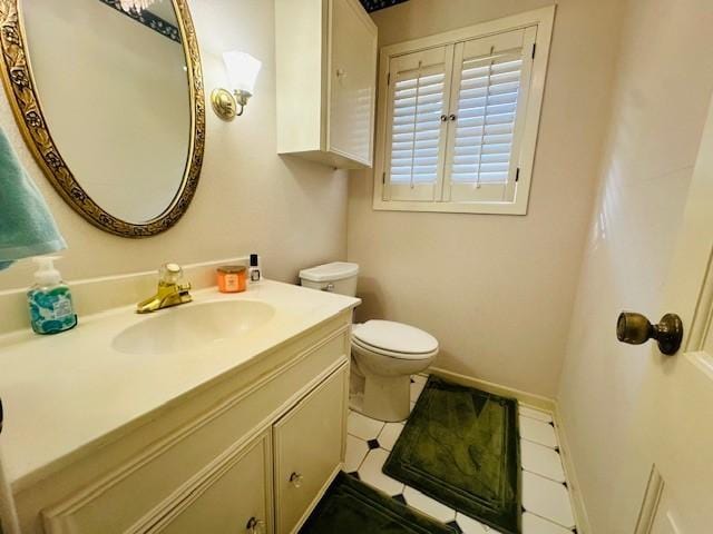 bathroom with toilet, vanity, and baseboards