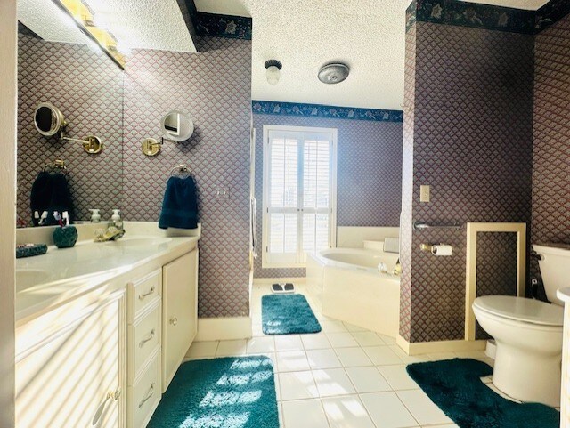 bathroom featuring tile patterned floors, toilet, a textured ceiling, vanity, and a washtub