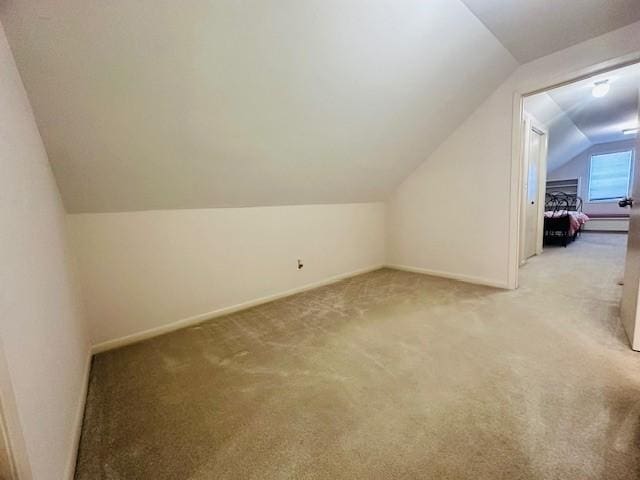 bonus room with light carpet, baseboards, and vaulted ceiling